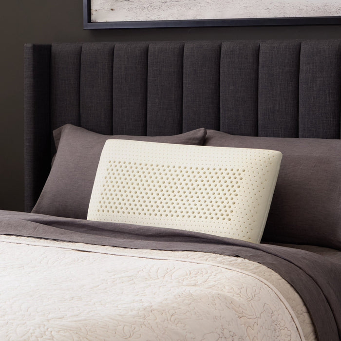 Malouf Zoned Talalay Latex Pillow latex core on a bed, three-quarter view