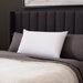 Malouf Zoned Talalay Latex Pillow in its white cotton cover on a bed
